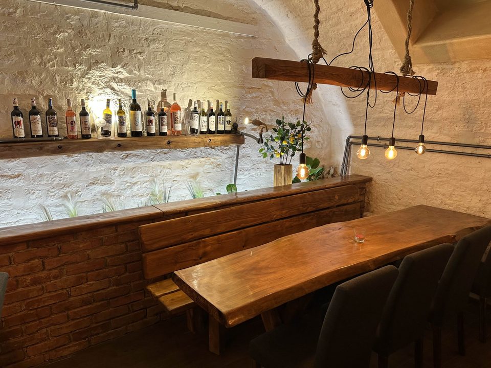 Gewölbekeller mit Natursteingewölbe, Weinregal und langer Holztafel